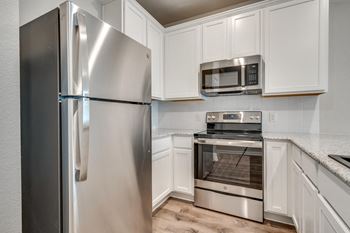 a kitchen with white cabinets and stainless steel appliances